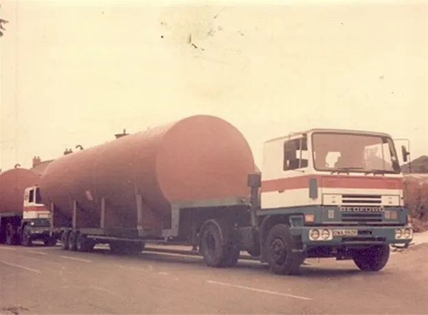 Vintage photo of an ABE-branded lorry with a large cylindrical tank trailer driving down a road