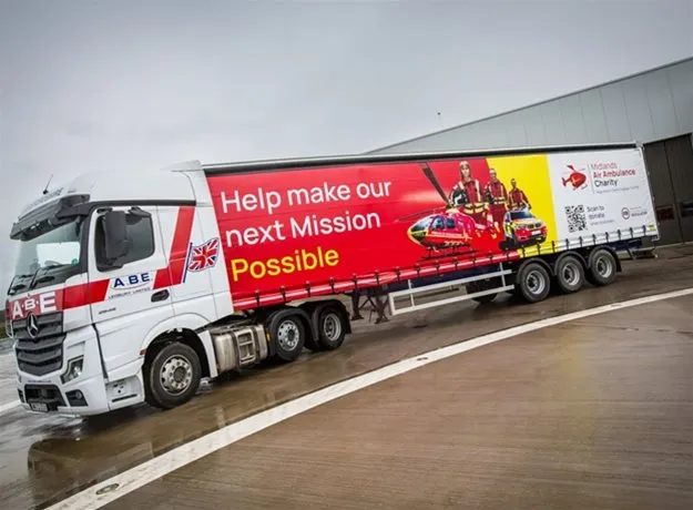 ABE logistics lorry featuring a full trailer wrap promoting the Midlands Air Ambulance Charity, with the message “Help make our next Mission Possible” alongside images of a helicopter and emergency service crew.